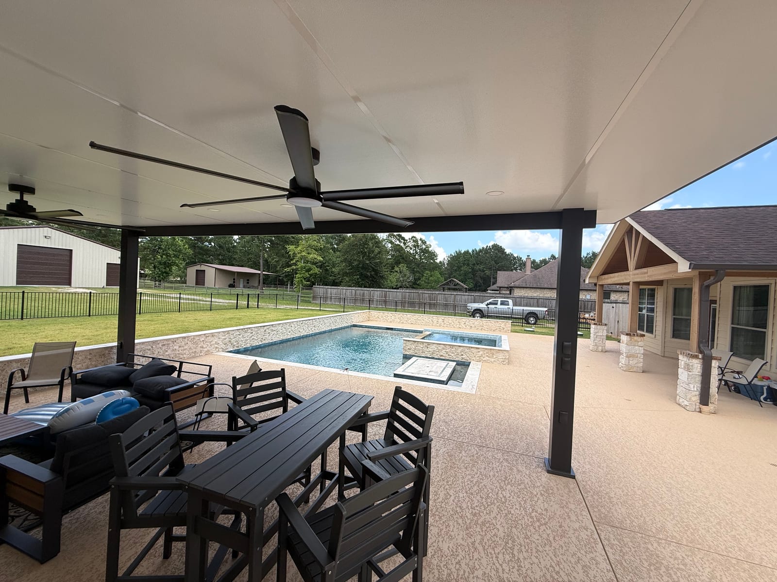 Covered patio with ceiling fans and a dining table looking out over a raised pool