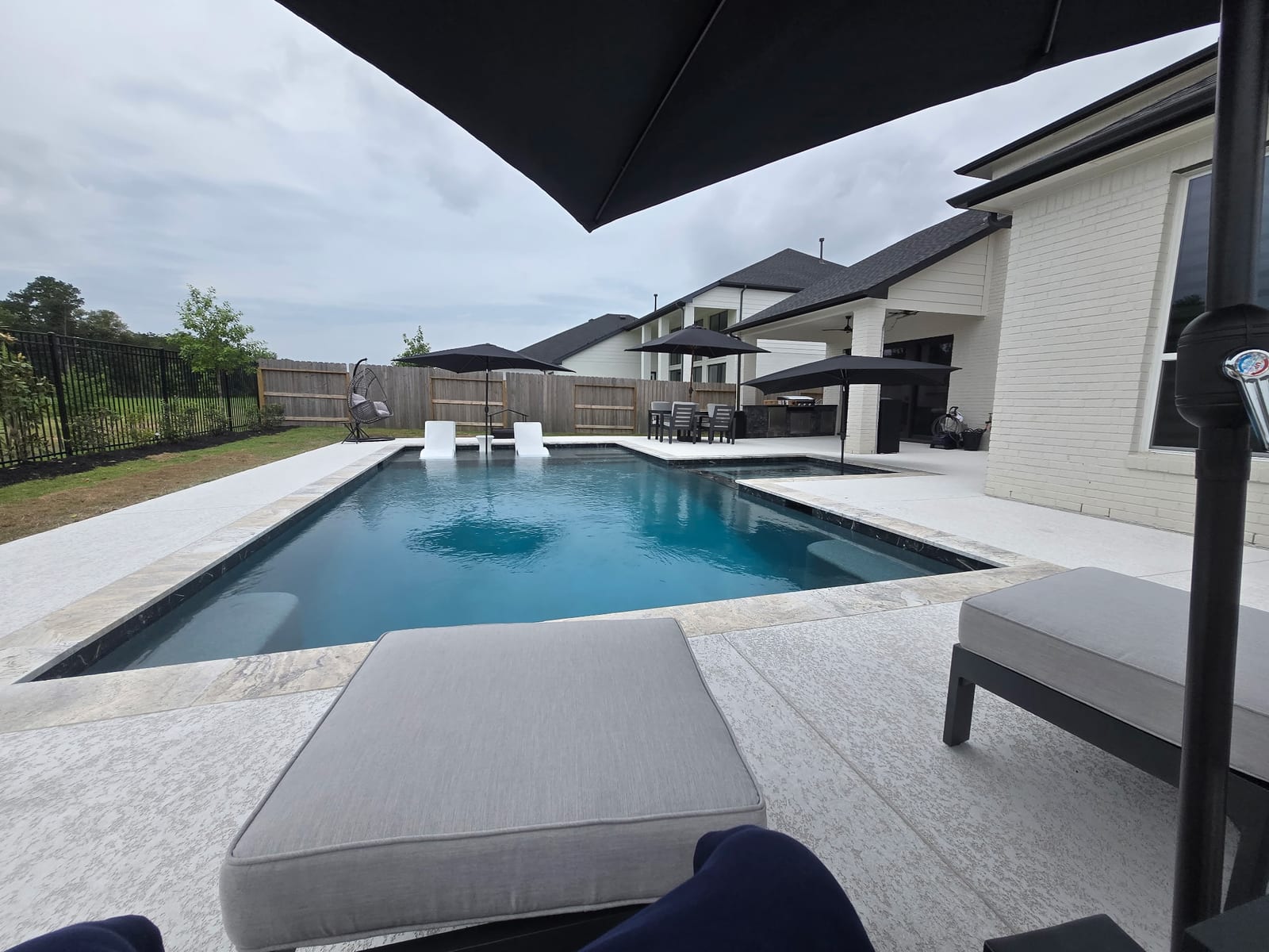 Tanning ledge with a white in-water lounger at the shallow end of the pool