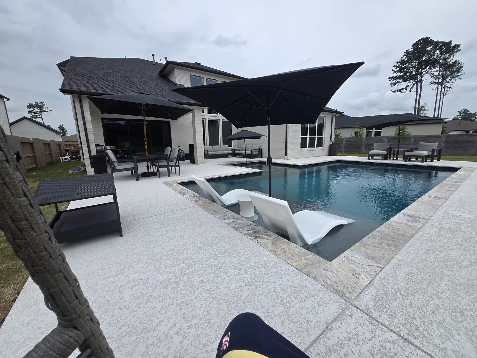 Poolside lounge seating and dining under umbrellas beside the pool deck