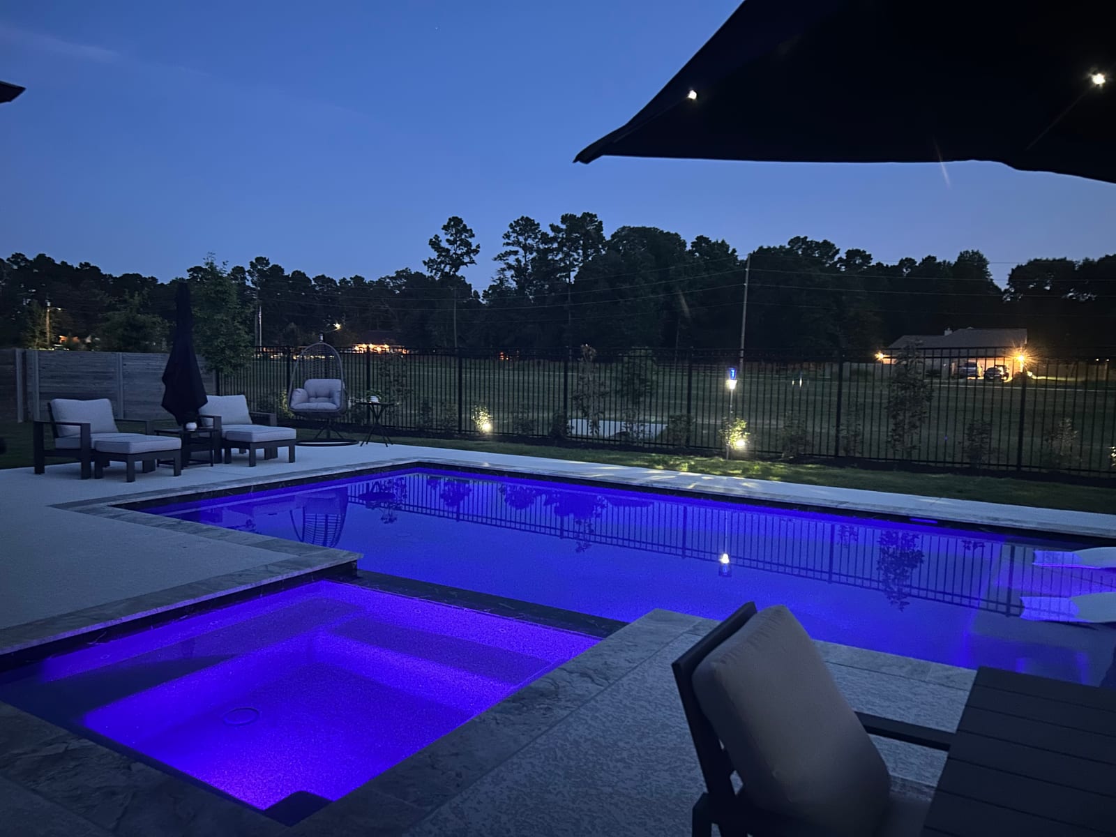 Pool and raised spa lit with colour LED lighting at dusk