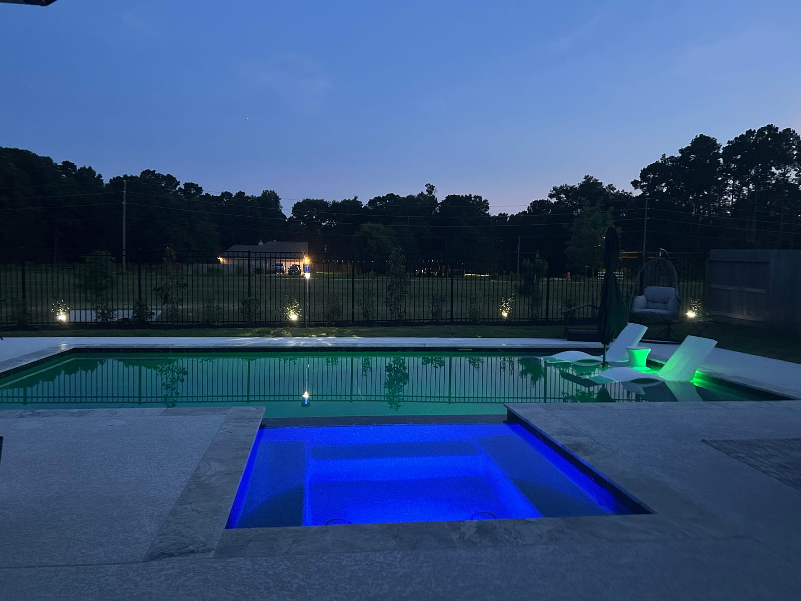 The spa glowing pale green above the deep blue pool at night