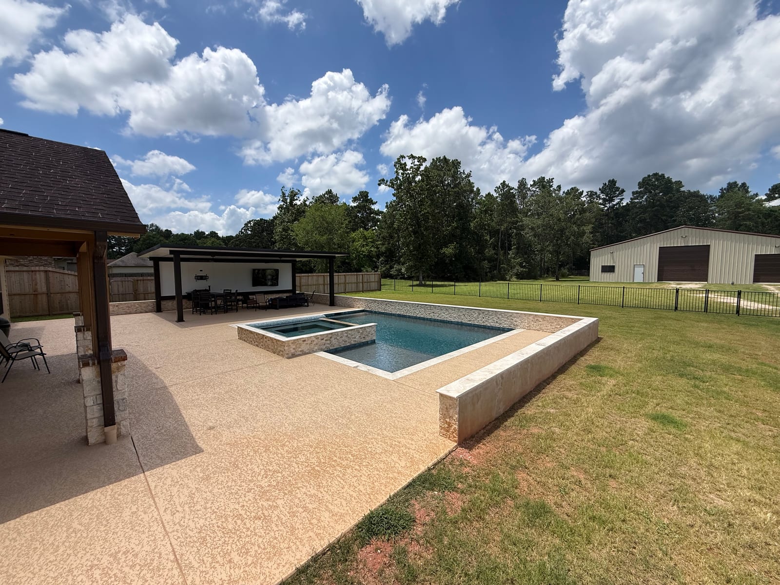 Raised rectangular pool and spa with a stone-faced wall above an open lawn